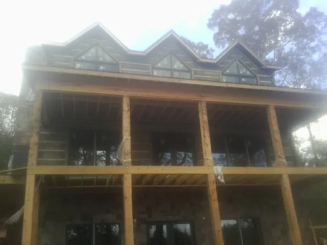 Dormers and porch framing on a large log home under construction — Roof Coating work by our crew in Altoona